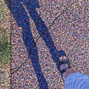 Schilderachtige afbeelding van een voet in een sandaal op een met schaduw bedekte kleurrijke stoep tijdens een zomerse wandeling.